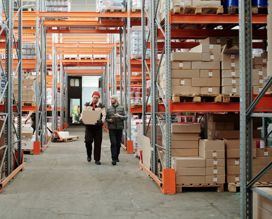 Bodega de distribución con estanterías y operarios cargando cajas